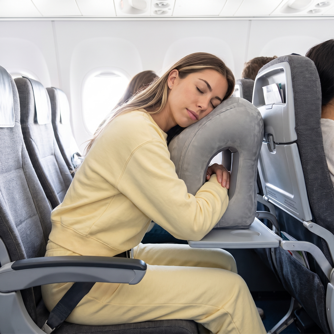 Woman sleeping on Skynap pillow on an airplane tray table